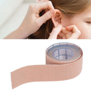 Person applying adhesive tape to ear with close-up of tape roll below.