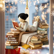 Decorative ornament of a girl reading books with 'Just a Girl Who Loves Books' text, against a blurred snowy window background.