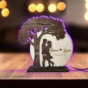 Decorative lamp with a tree design and 'James Linda forever' text on a wooden surface.