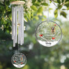 Personalized wind chime with engraved dog image and text, hanging among green leaves.