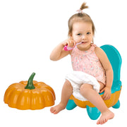 Child sitting on a pumpkin-shaped potty chair with a toy pumpkin next to them.